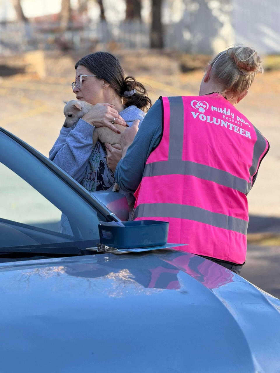 Shawna Anderson holding a puppy next to a rescue volunteer at a community event